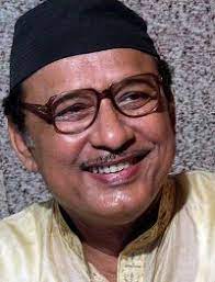 Khagen Mahanta, the renowned Assamese folk singer known as the "Bihu Samrat," wearing glasses and a black cap, smiling in a candid moment.