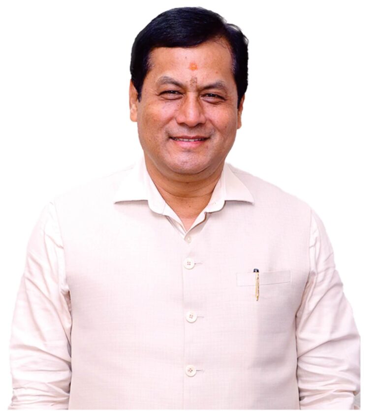 Sarbananda Sonowal, former Chief Minister of Assam, smiling in formal attire, with the Indian flag in the background, symbolizing his leadership and service.
