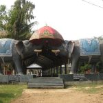 Gateway of Dhekiakhowa Bornamghar, featuring two large elephant sculptures adorned with intricate golden-colored decorations and a grand ornamental canopy, marking the entrance to the sacred site.