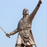 A statue of Lachit Borphukan, the legendary Ahom general, holding a sword and raising his hand in a commanding stance, symbolizing courage and leadership.