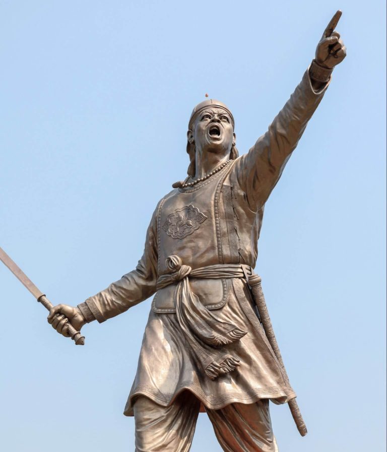A statue of Lachit Borphukan, the legendary Ahom general, holding a sword and raising his hand in a commanding stance, symbolizing courage and leadership.