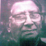 A vintage black-and-white photograph of Syed Abdul Malik, an eminent Assamese writer, wearing glasses and a suit, with a thoughtful expression.