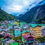 Colorful houses nestled in the lush green mountains of Sikkim under a cloudy sky.