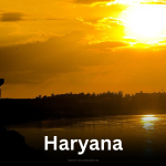 Sunset over the Yamuna River with a traditional pavilion silhouette in Haryana.