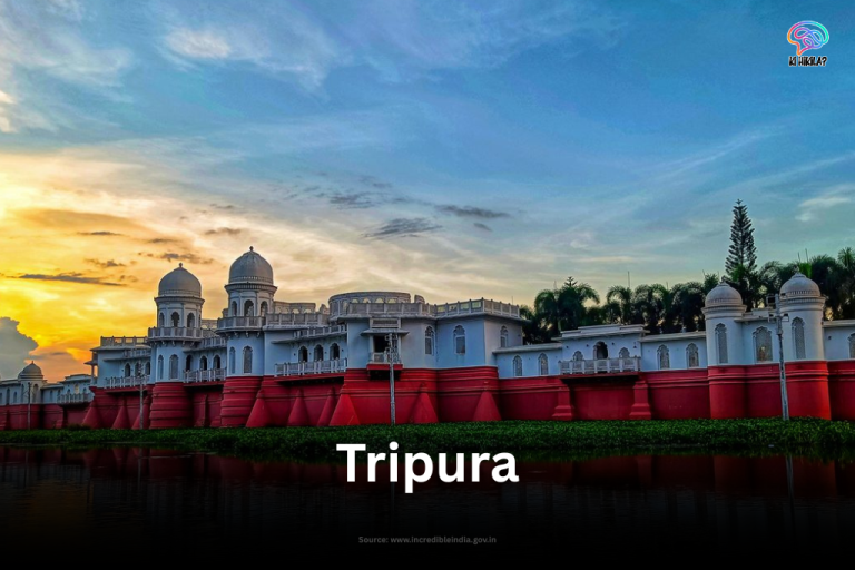 The magnificent Neermahal palace, with its white domes and red base, reflecting on the tranquil Rudrasagar Lake in Tripura at sunset.