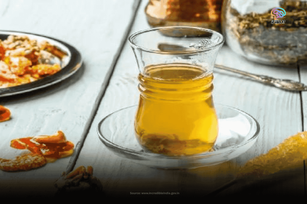 The Fascinating Story of Jammu and Kashmir: History Before 1947, Unique Climate, Tourism, Economy & Culture A clear glass filled with golden Kahwa, a traditional Kashmiri tea, sits on a white table with dried fruits and nuts in the background, showcasing the local beverages of Jammu and Kashmir.