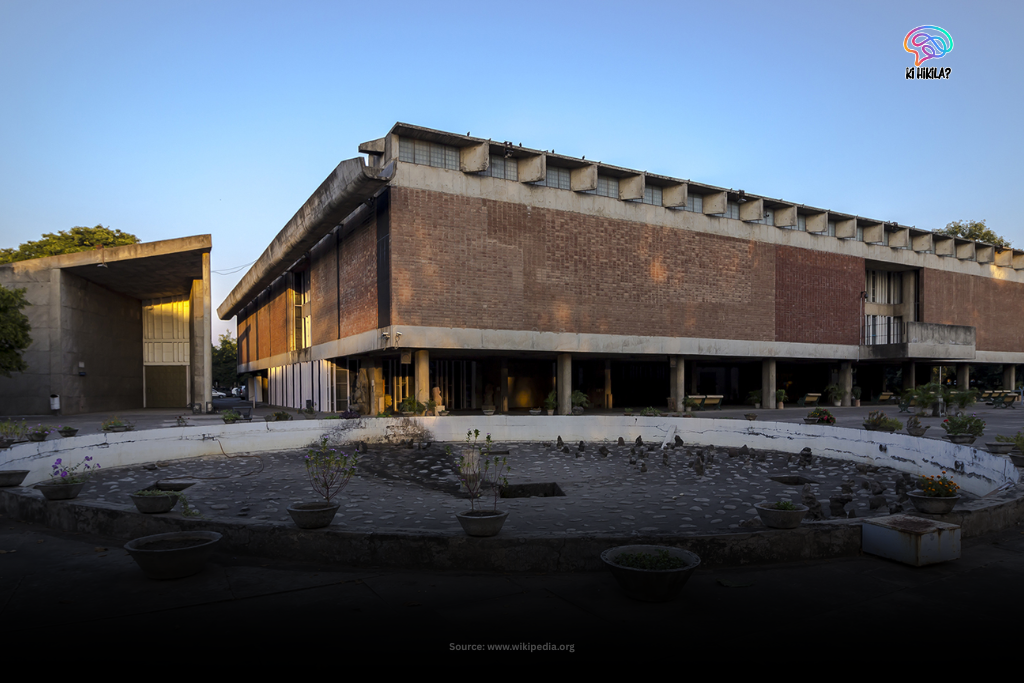 The facade of the Government Museum and Art Gallery in Chandigarh, a modernist brick building with a large mural, seen from across a green lawn.