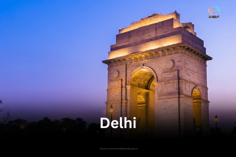 The illuminated arch of India Gate, a prominent war memorial in Delhi, standing against a deep blue twilight sky.