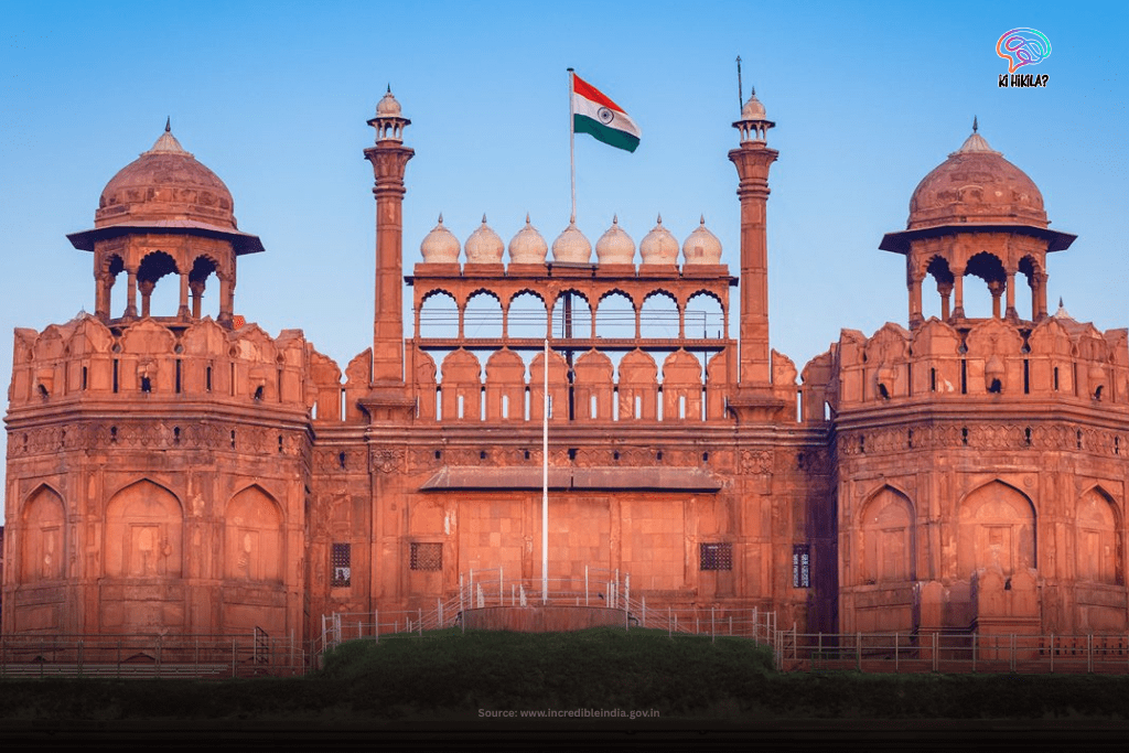 The sunlit red sandstone walls of the iconic Red Fort in Delhi, with the Indian flag flying above its ramparts.