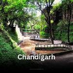 A wide-angle view of the Rock Garden in Chandigarh, showing numerous sculptures made from recycled materials set against a backdrop of artificial waterfalls.