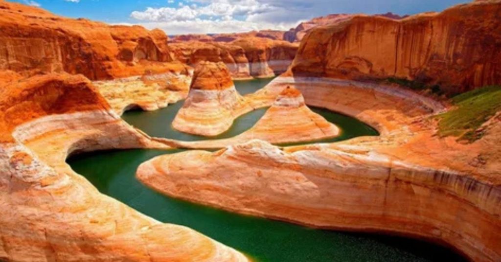 Wonderful Natural Wonder: How Grand Canyons Are Formed A breathtaking view of a winding canyon with layered red rock formations and a greenish river curving through it, showcasing erosion and sedimentary layering.