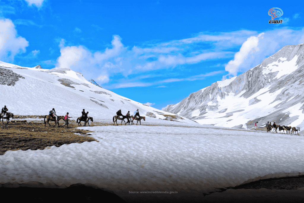 The Fascinating Story of Jammu and Kashmir: History Before 1947, Unique Climate, Tourism, Economy & Culture Pilgrims on horseback traverse a snow-covered mountain path in Jammu and Kashmir, with majestic, snow-capped peaks rising in the background.