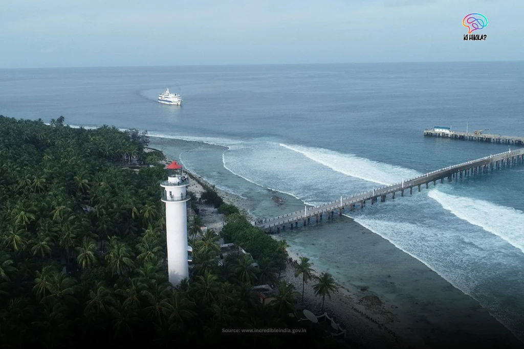 Lakshadweep: A Complete Guide to India’s Coral Paradise, Culture, and Islands A white lighthouse and a long jetty on an island in Lakshadweep, with a passenger ship visible on the calm ocean.