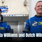 Sunita Williams and Butch Wilmore in white spacesuits smiling and holding orange roses, standing together before their space mission launch.