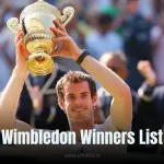 Wimbledon Winners List: A jubilant tennis player in a white outfit raising a golden Wimbledon trophy with both hands, smiling as a cheering crowd in formal attire blurs in the background.