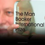 A person's hands holding the transparent, glass trophy for "The Man Booker International Prize.